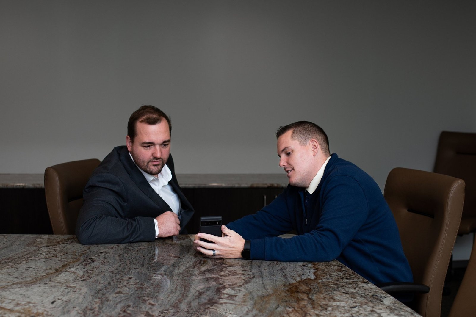 Ian S. Hoover at a conference table reviewing a phone with a colleague.